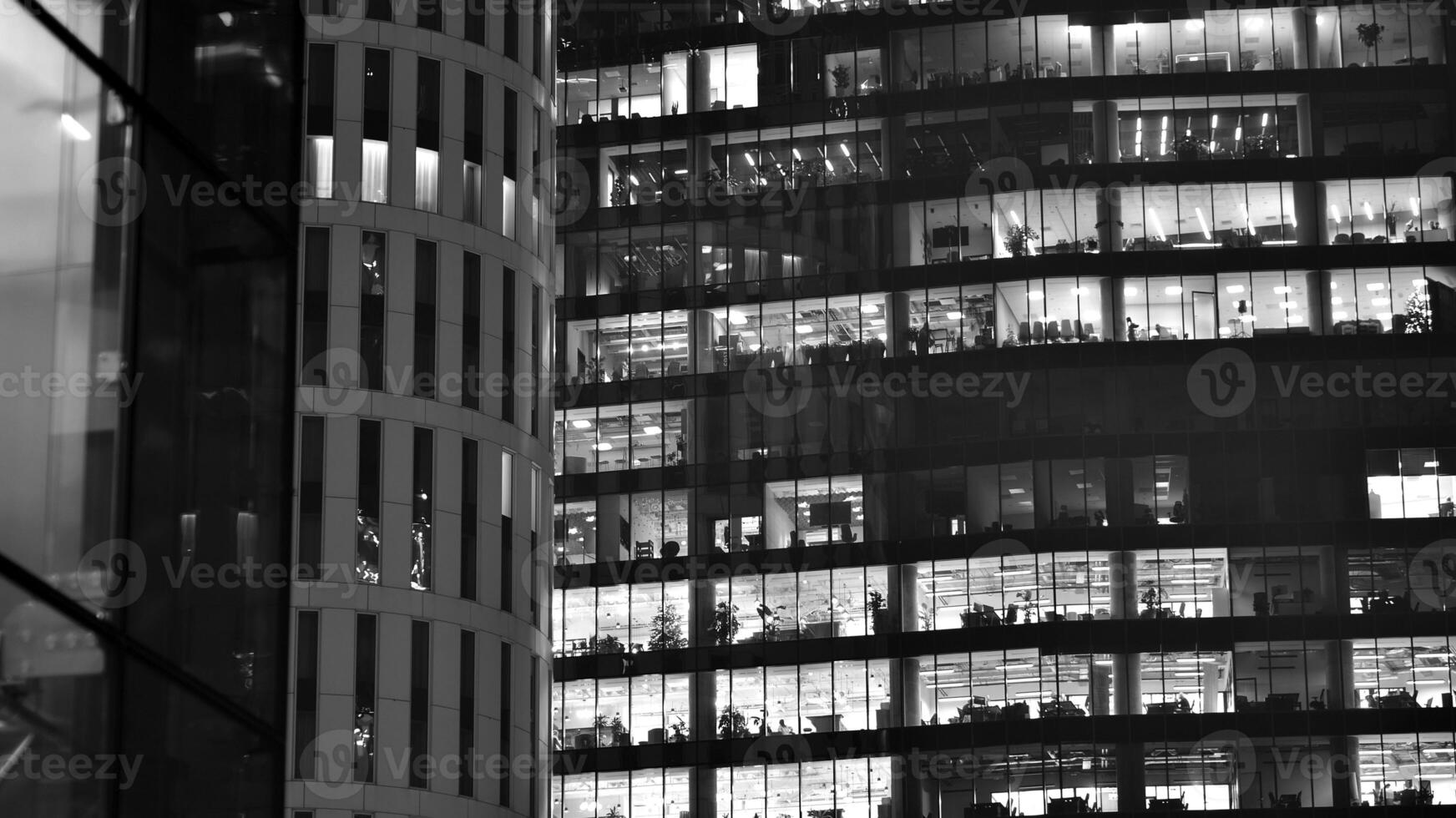 Pattern of office buildings windows illuminated at night. Glass architecture ,corporate building at night - business concept. Black and white. photo