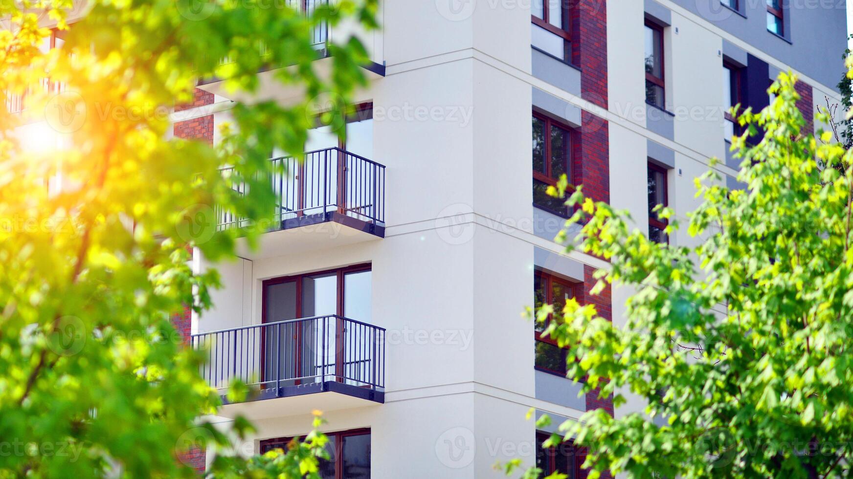 Modern residential building with new apartments in a green residential area. Eco architecture. Green tree and new apartment building. The harmony of nature and modernity. photo