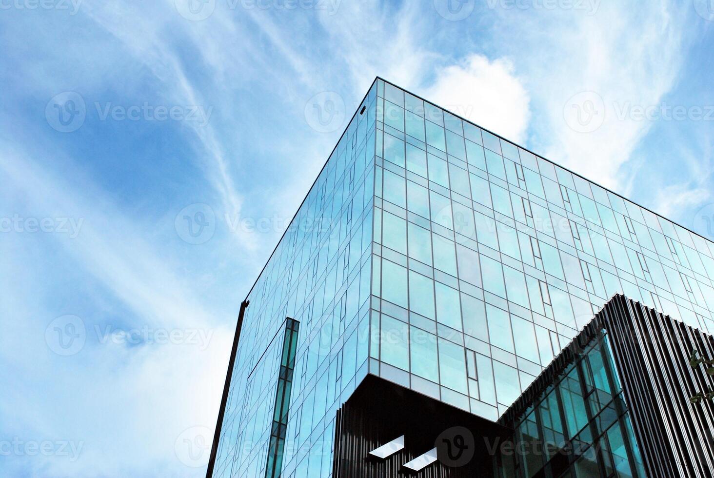 Glass building with transparent facade of the building and blue sky. Structural glass wall reflecting blue sky. Abstract modern architecture fragment. Contemporary architectural background. photo