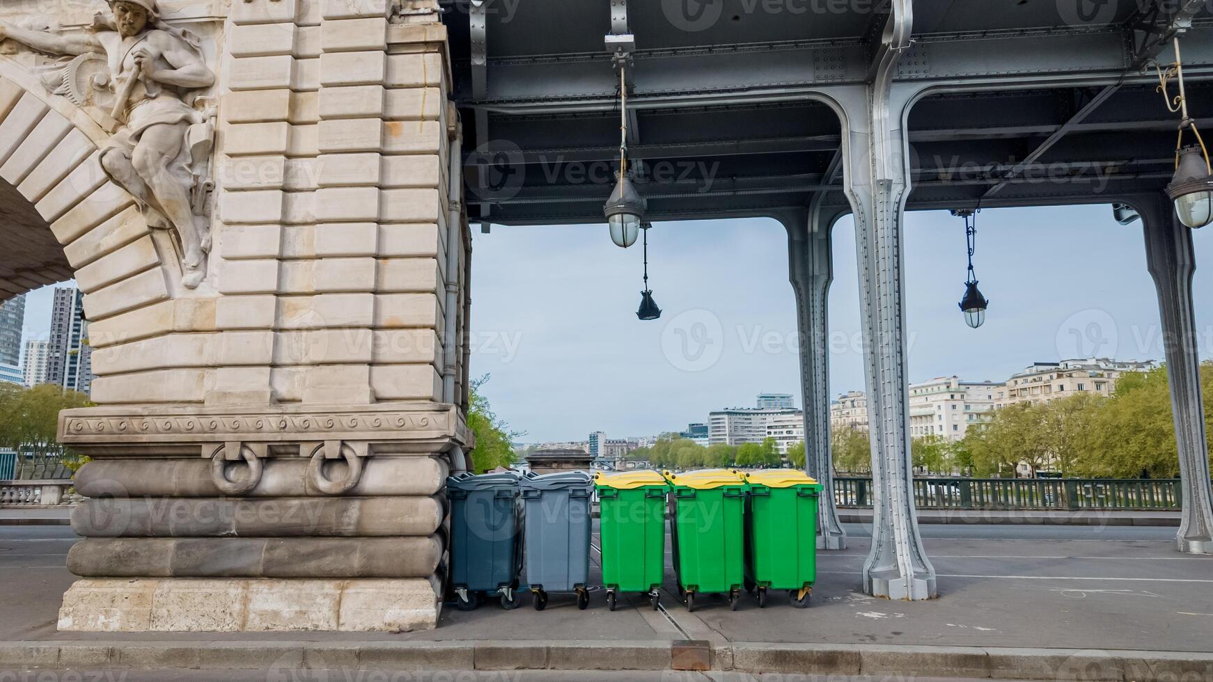 Colorful recycling bins lined up under a bridge in an urban setting, representing waste management and environmental conservation concepts photo
