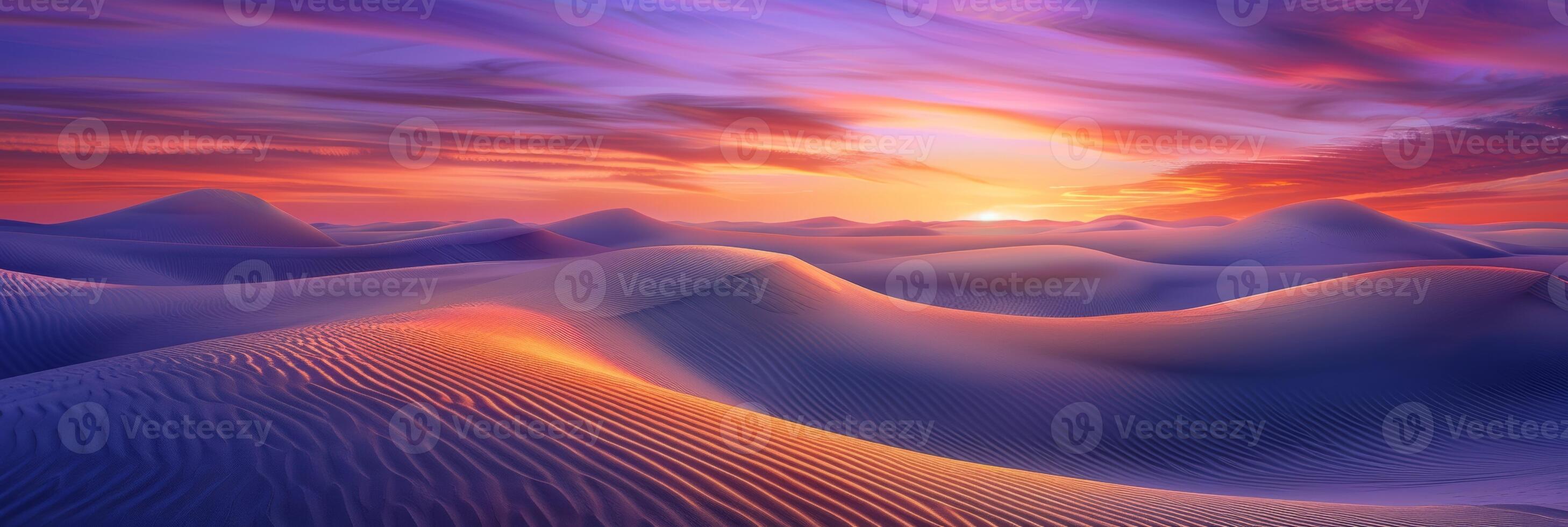 Sunrise paints unusual fractal patterns on undulating desert sand dunes with a vibrant orange and purple gradient sky as backdrop photo