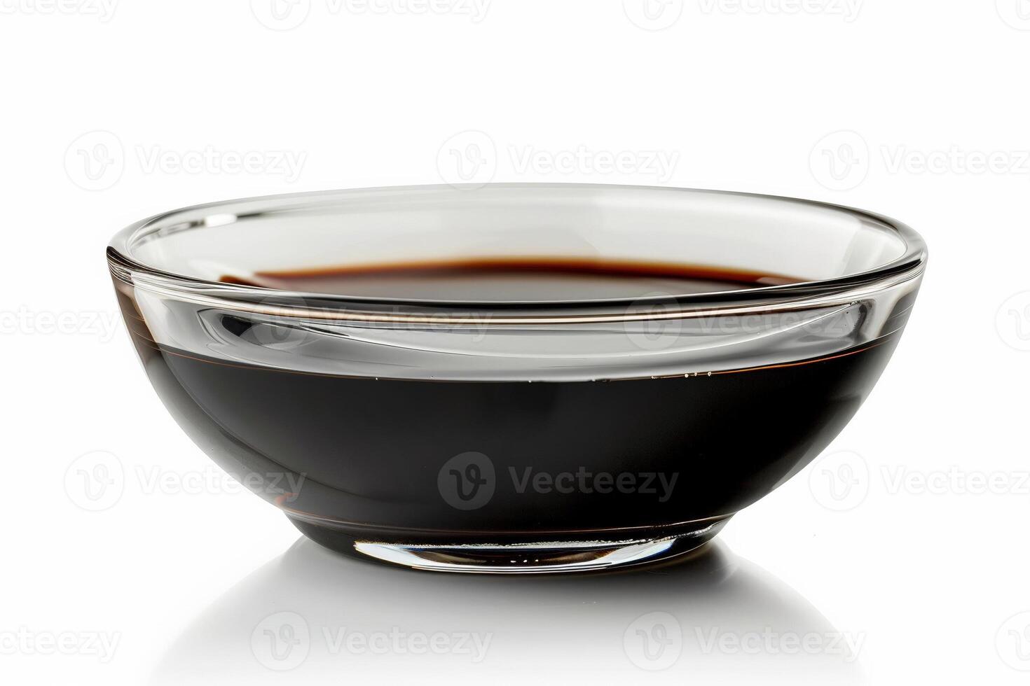 Glass bowl of balsamic reduction, glossy and dark, elegantly presented isolated on white photo