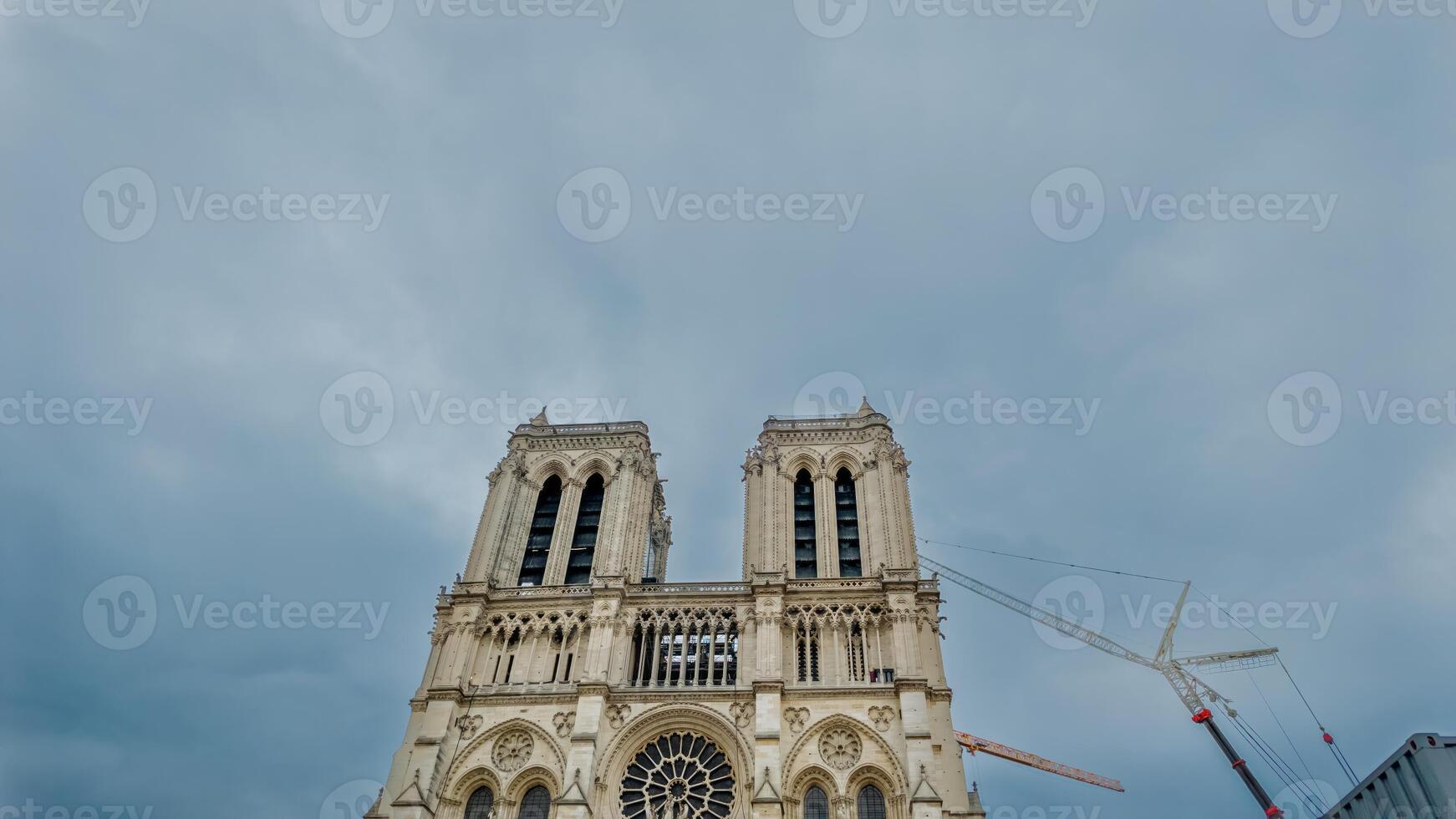 Majestic Notre Dame Cathedral in Paris under restoration with cranes against a cloudy sky, symbolizing cultural heritage and European architecture photo