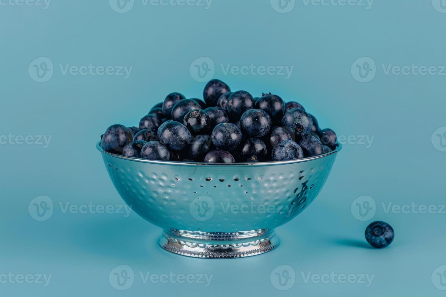 blueberries in a silver bowl isolated on a blue gradient background photo