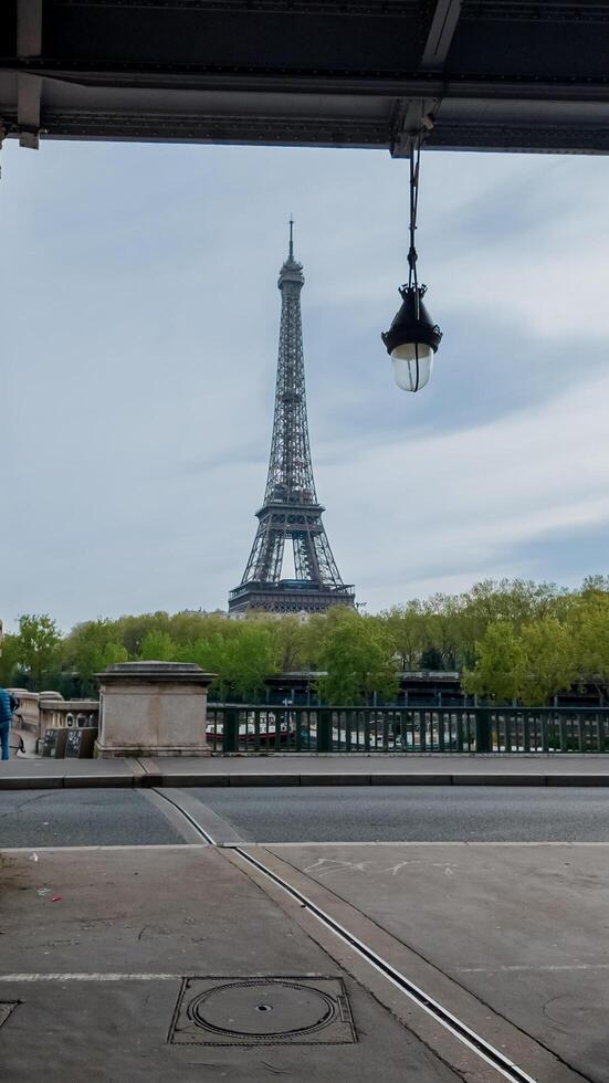primavera ver de el eiffel torre desde un parisino calle con en ciernes árboles, capturado en París, Francia, en abril 14, 2024, ideal para viaje y fiesta temas foto