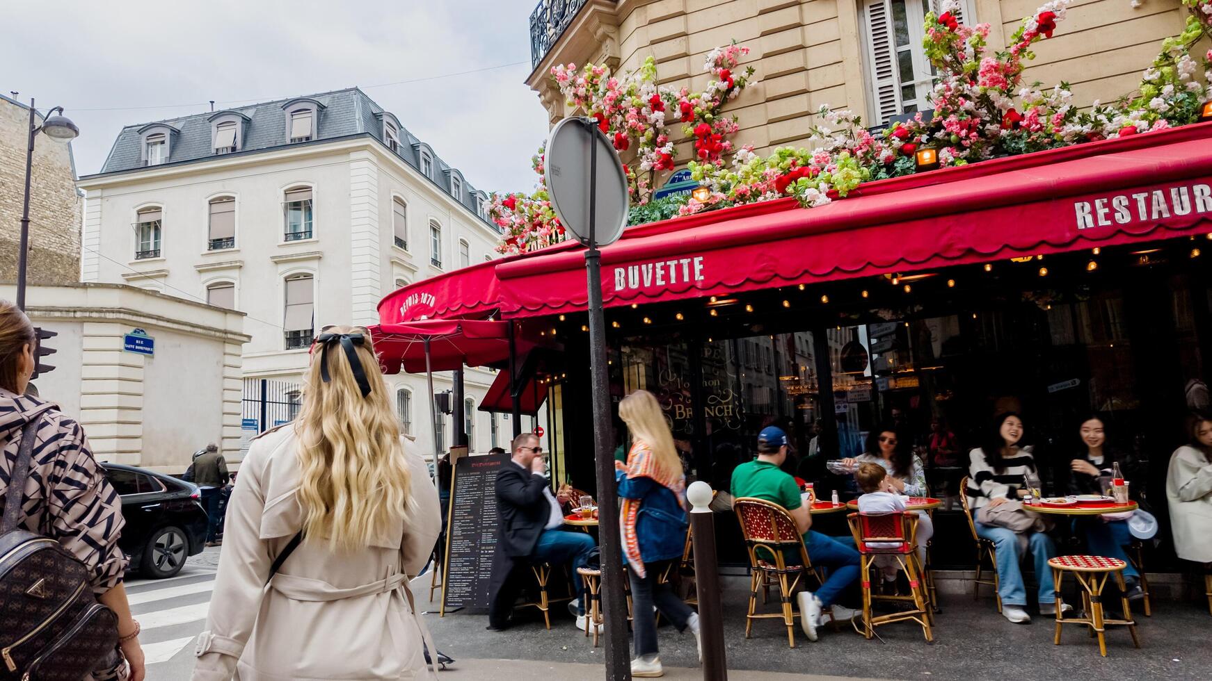 diverso mecenas disfrutando al aire libre comida a un flor adornado parisino pequeño restaurante en un animado esquina en París, Francia, simbolizando europeo cultura y ocio, abril 14, 2024 foto