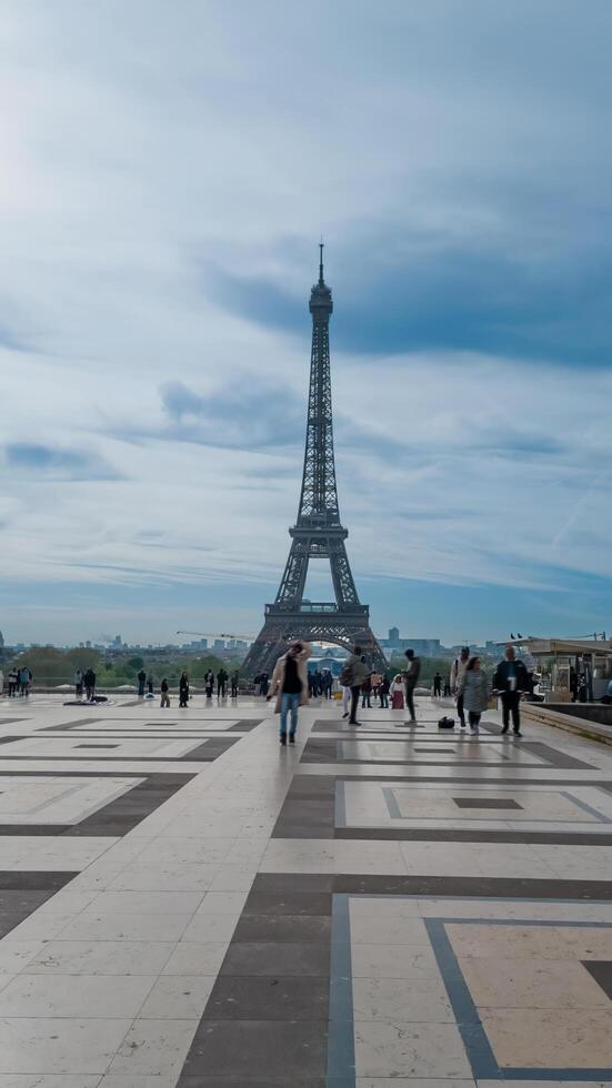 Visitors strolling near the iconic Eiffel Tower on a cloudy spring day in Paris, France, April 14th, 2024 perfect for travel and European landmarks themes photo