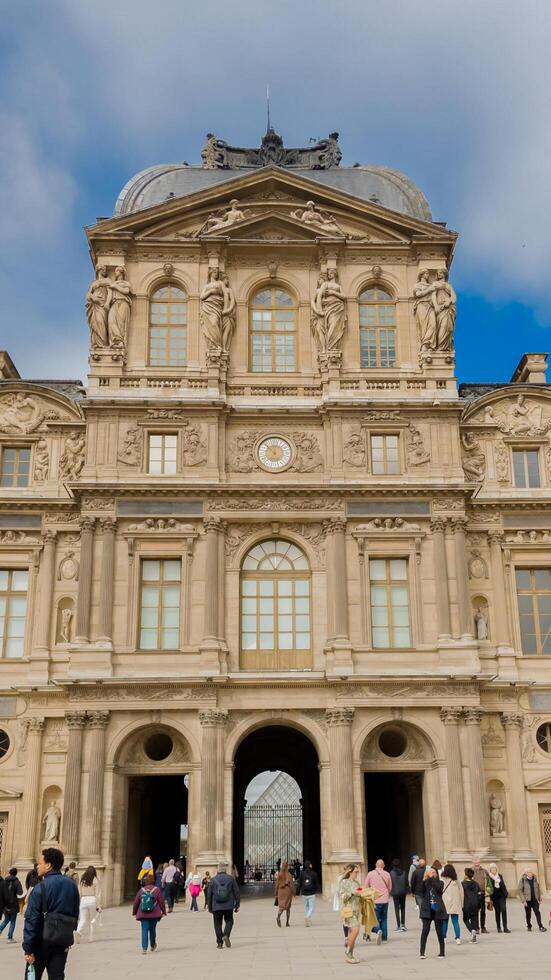 Tourists exploring the historic architecture of the Louvre Museum in Paris, France, on a clear day, April 14th, 2024, ideal for travel and cultural themes photo