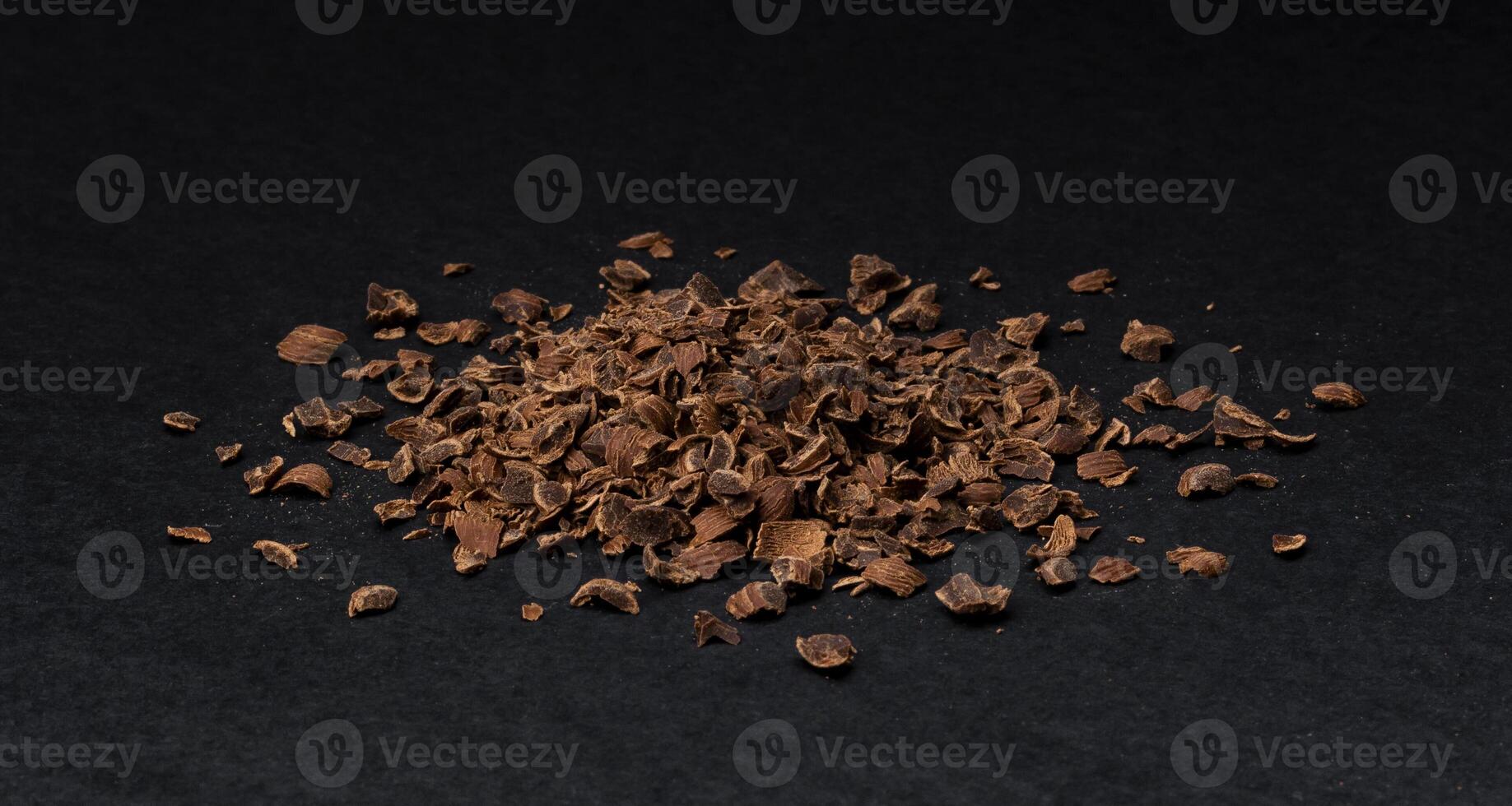 Grated chocolate. Heap of ground chocolate isolated on black background, closeup photo