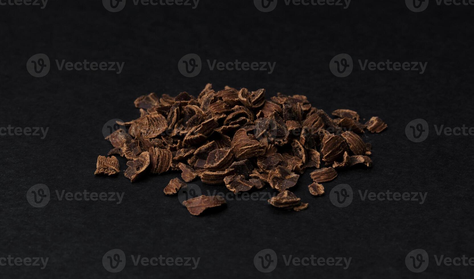 Grated chocolate. Heap of ground chocolate isolated on black background, closeup photo