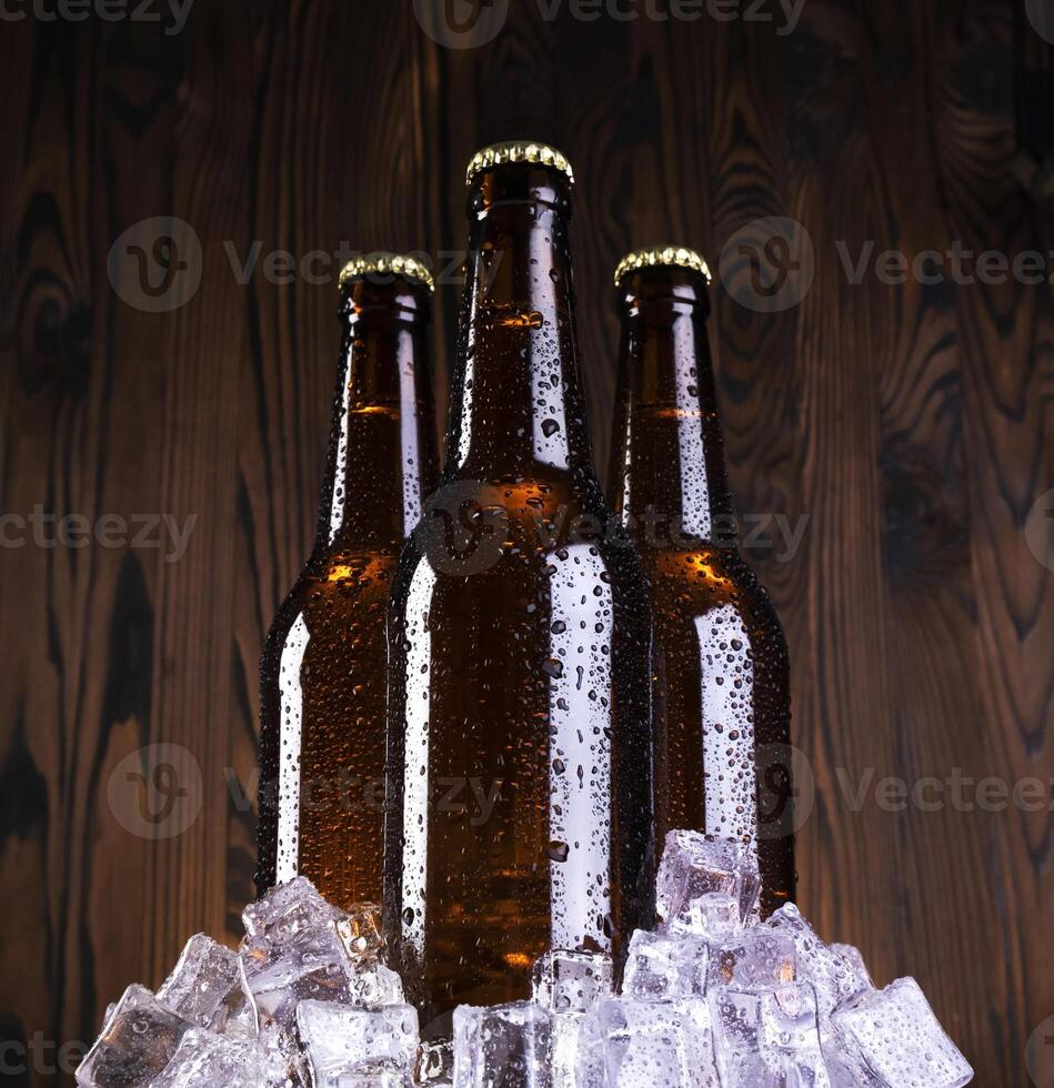 frío cerveza con agua gotas, cerveza botellas con hielo cubitos foto