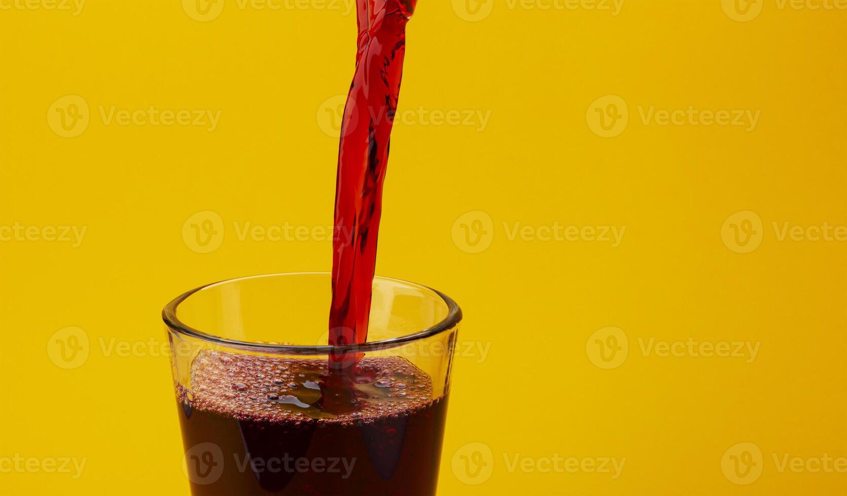 Pouring cherry juice isolated on yellow background with copy space photo