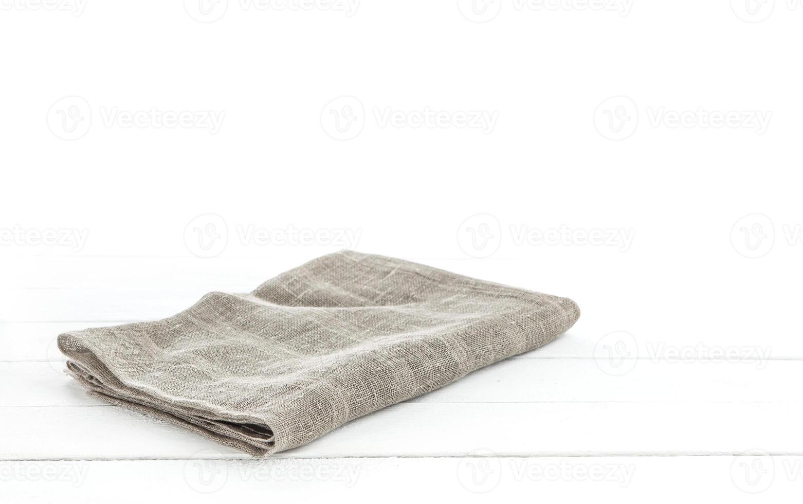 Folded Burlap hessian or sacking tablecloth on white wooden background for product montage photo