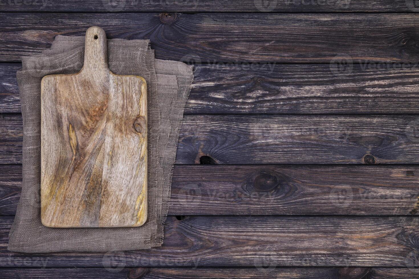 Old cutting board on dark wooden table. Top view. Copy space photo