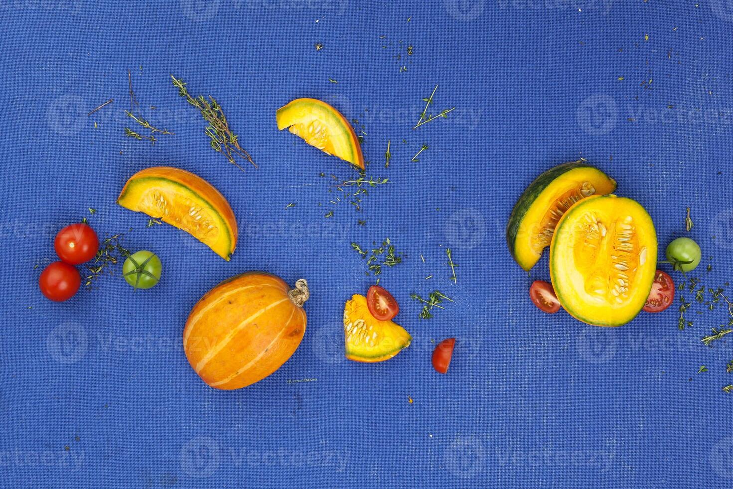 Food concept background. Pumpkin, tomatoes and thyme on blue table. Top view photo