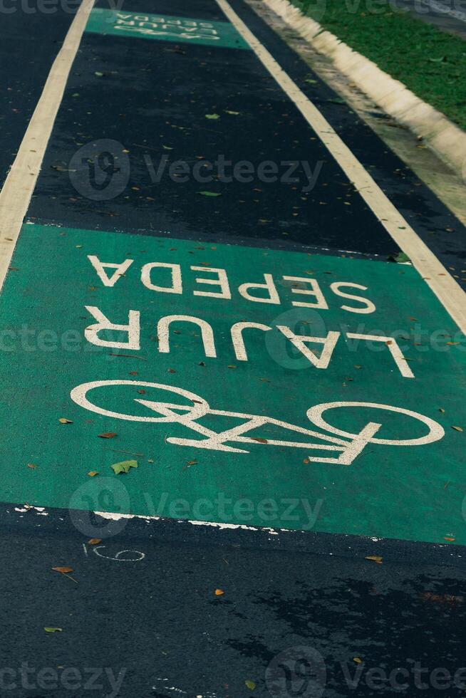 bicicleta carril firmar en amarillo con sólido líneas en asfalto la carretera en Indonesia foto