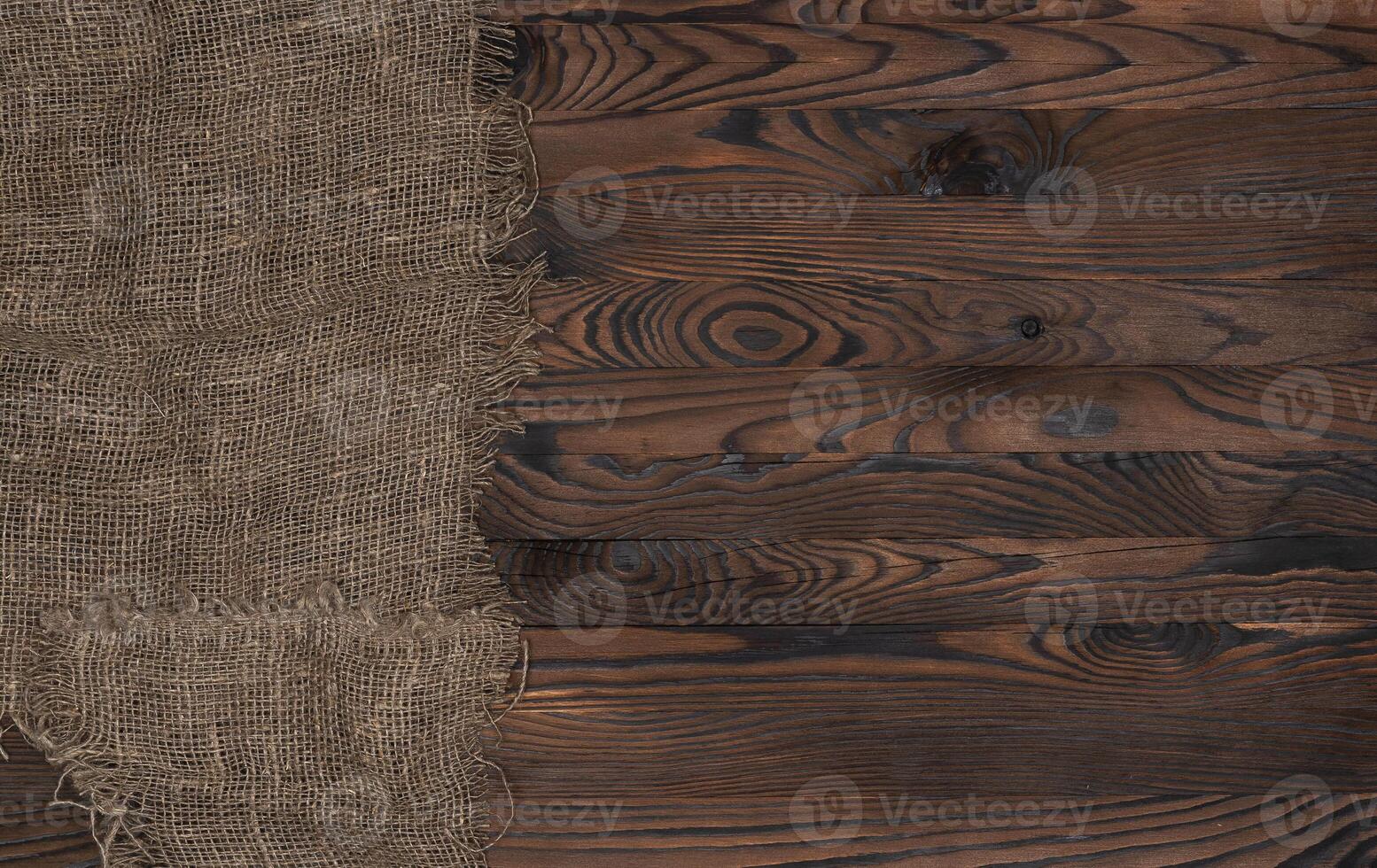 Old burlap fabric napkin on brown wooden background, top view photo