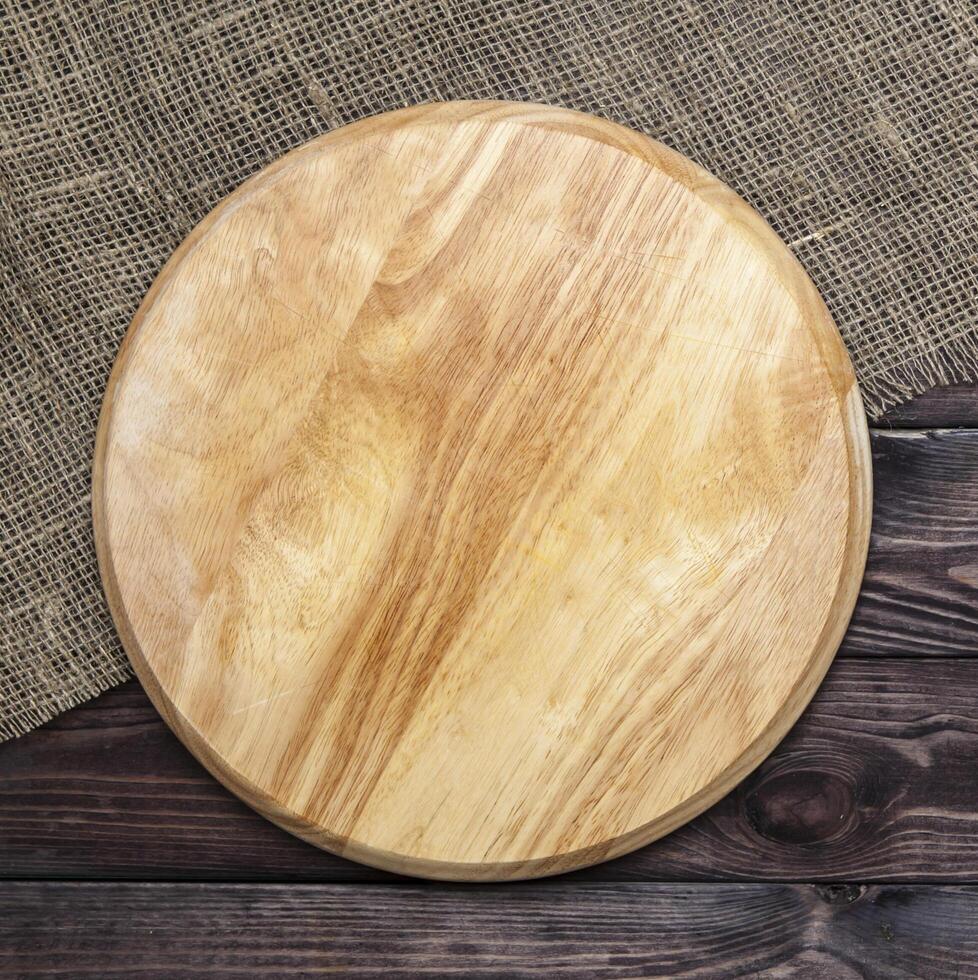 Round cutting board on a wooden table, top view photo