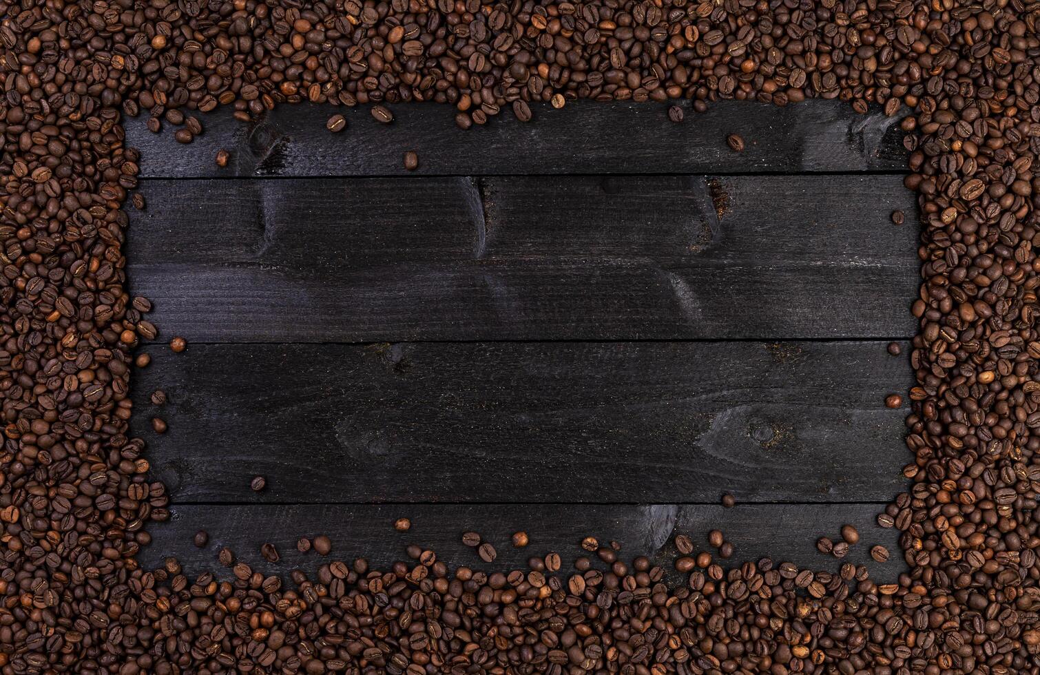 Frame made of roasted coffee beans on black wooden background, top view photo