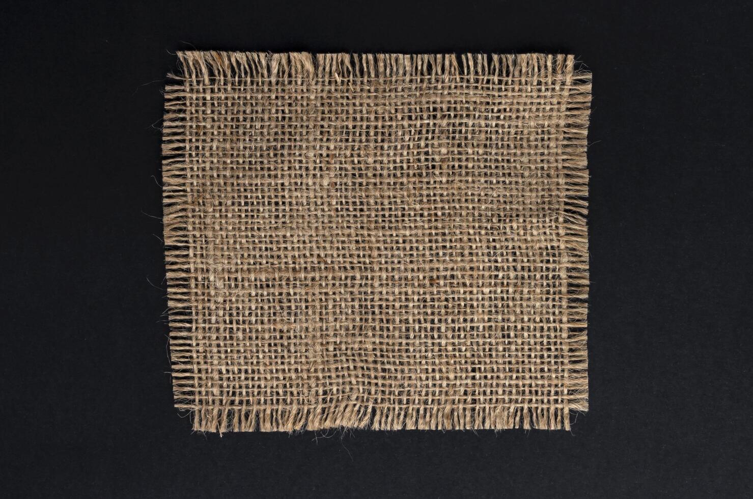 Old burlap fabric napkin on black background, top view photo