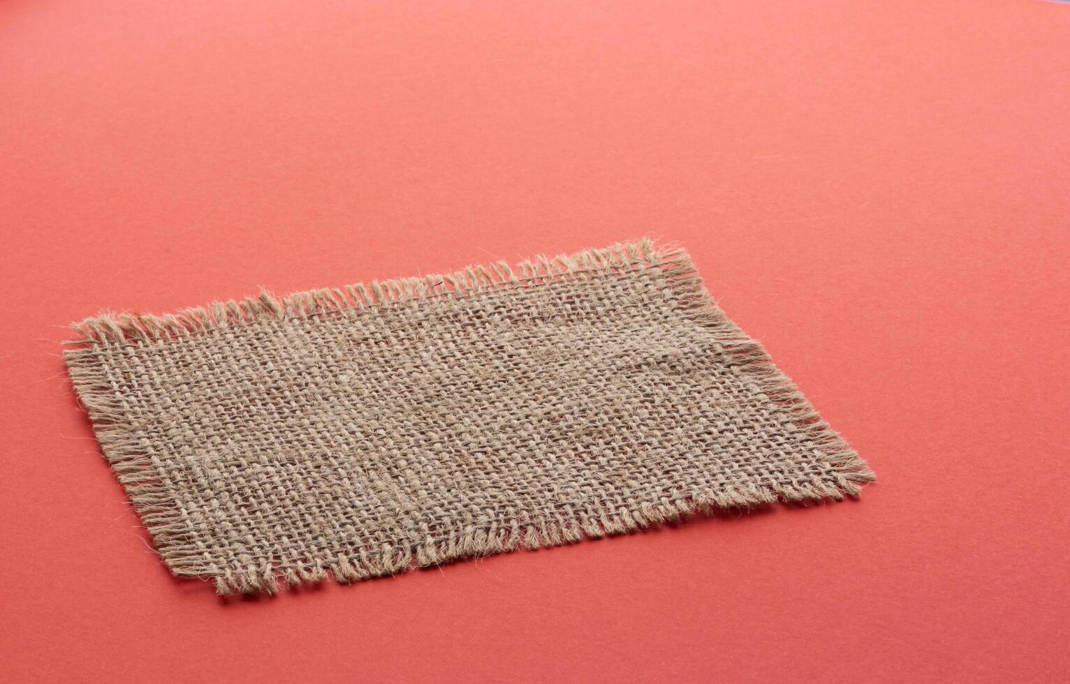 Burlap napkin on red color background photo