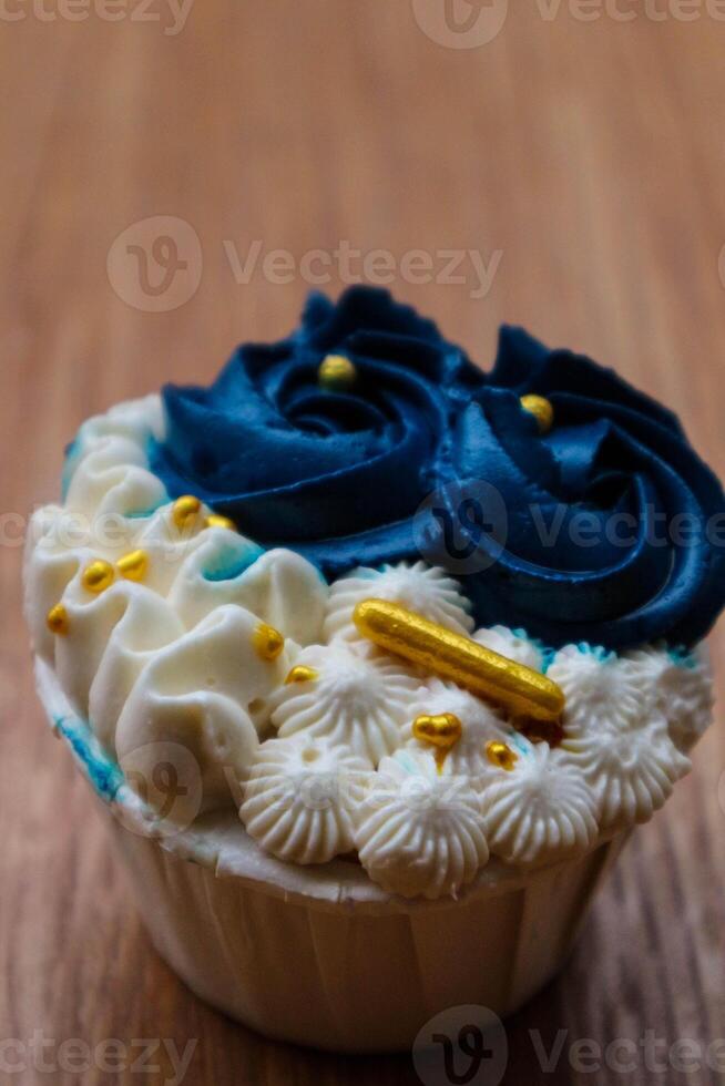 Luxurious and elegant cupcakes, with white cream and navy blue with gold sprinkles. photo