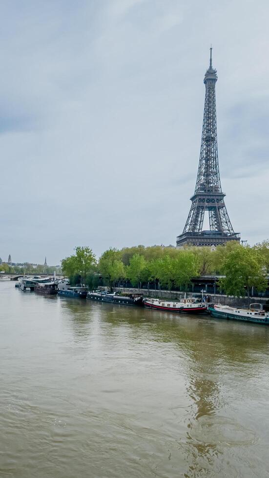 Springtime view of the Eiffel Tower and Seine River with moored boats in Paris, France, captured on April 14th, 2024, ideal for travel and tourism themes photo