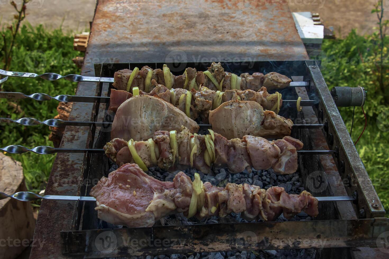 Cooking kebabs on a grill with smoke. Fresh brown BBQ meat cooked on an outdoor grill photo