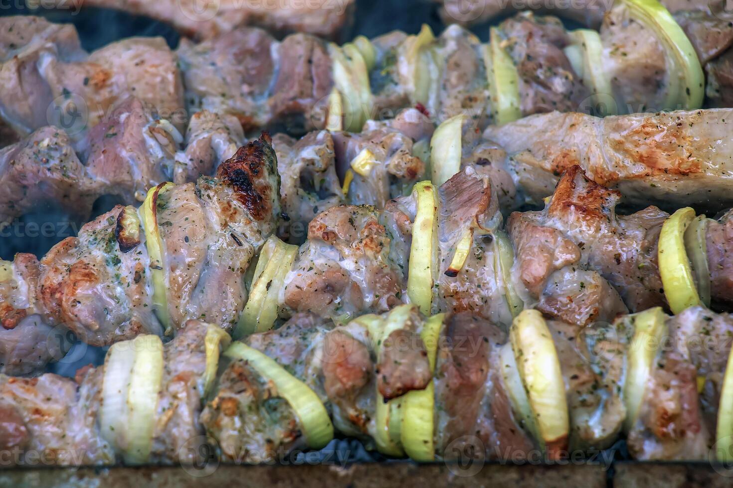 Cooking kebabs on a grill with smoke. Fresh brown BBQ meat cooked on an outdoor grill photo
