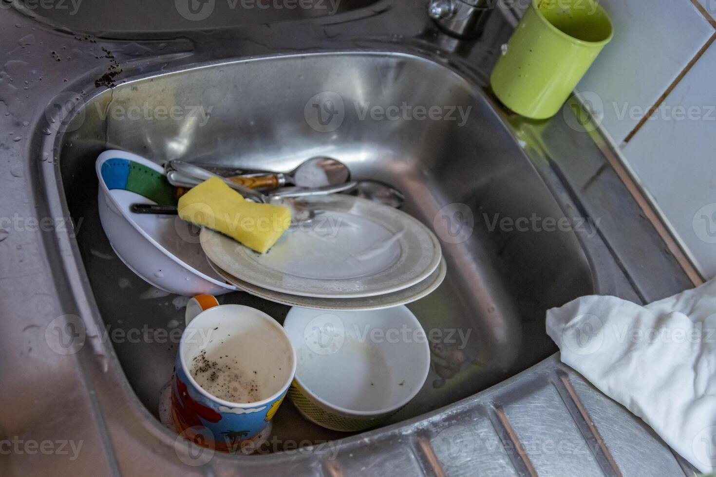 Cleaning the dishes. Dirty cups, plates, knives, forks and spoons are being washed in the sink of the camping kitchen. Washing utensils. Metal working surface of the counter. Top view. Selective focus photo