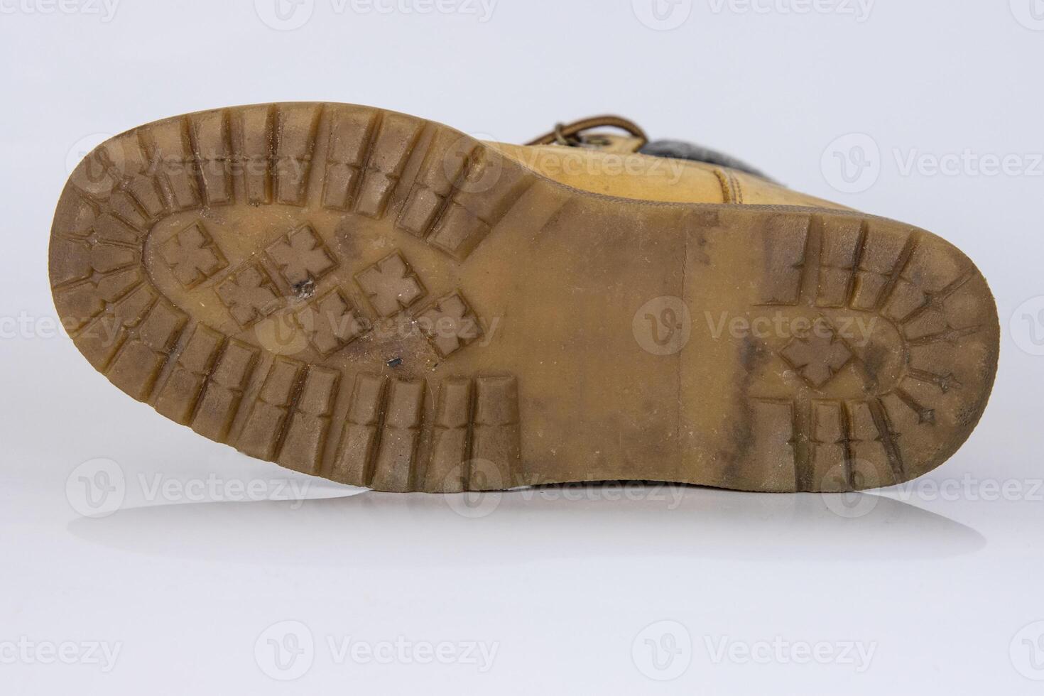 Yellow sole, bottom of hiking trekking lace boots Isolated on white glossy surface with beautiful reflection effect. Second hand tourist walking shoes. Copy Space. White background. photo