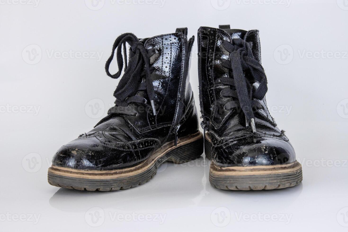 Frontal view of a very worn pair of boots. Old used broken Black Leather lace high Boots. Trendy ankle boots. Stylish womens mens unisex Grunge boots with bootlace. isolated on white background photo