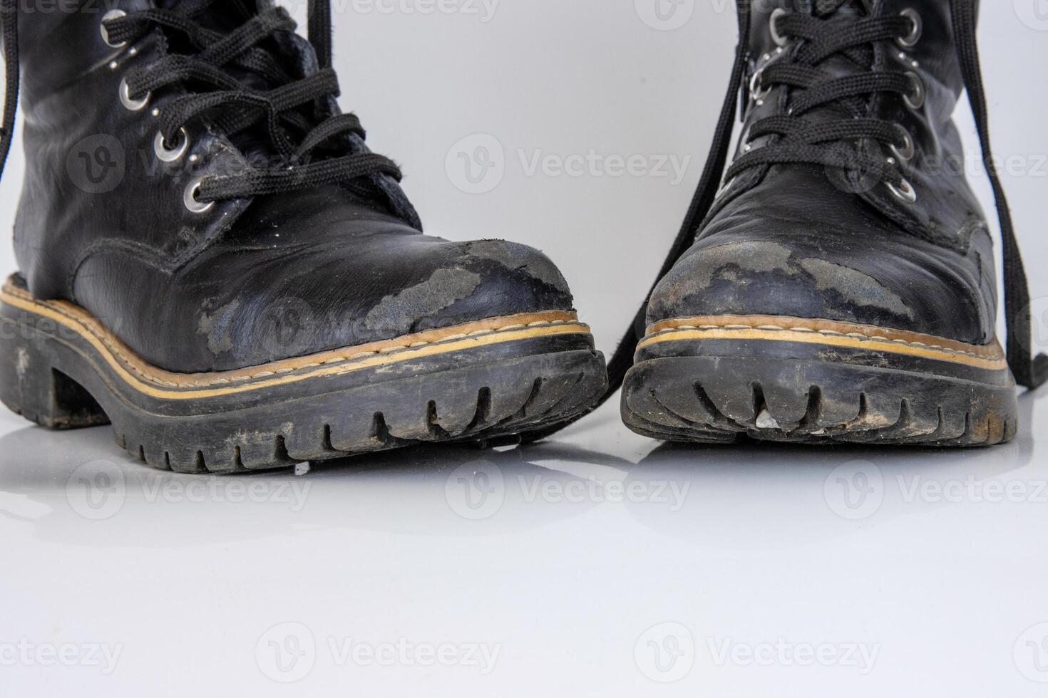 Frontal view of a very worn pair of boots. Old used broken Black Leather lace high Boots. Trendy ankle boots. Stylish womens mens unisex Grunge boots with bootlace. isolated on white background photo