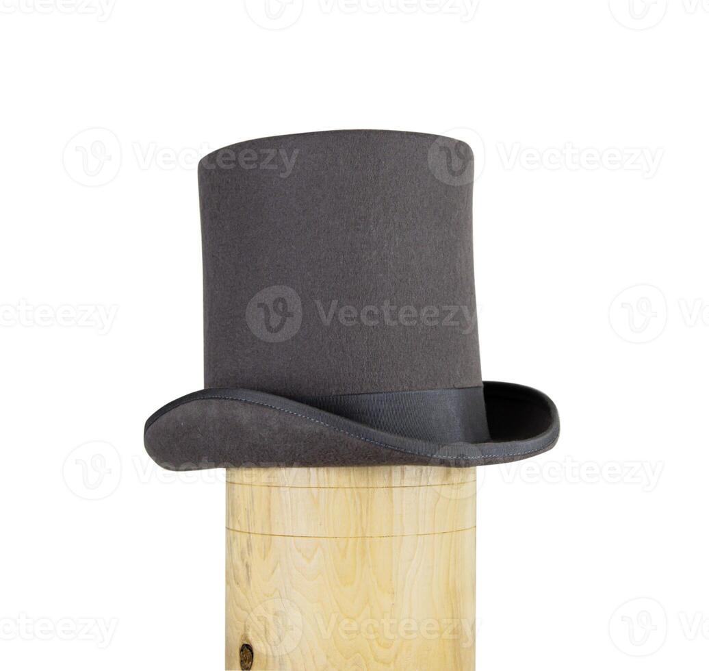 Magic hat. Topper. Elegant vintage gray beige wool felt top hat with black band on the wooden hat block. Grosgrain ribbon trim around rolled brim. Isolated on white background. Close-up. Copy space. photo