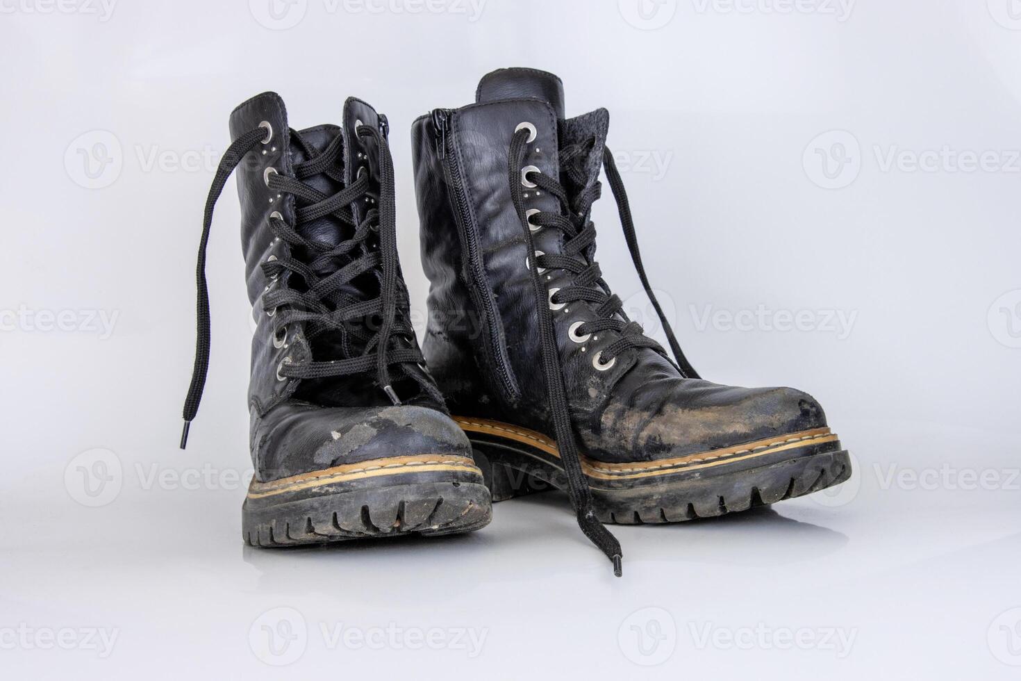 Old used broken Black Leather Army lace Boots. Trendy autumn boots. Stylish womens mens unisex Grunge boots with bootlace. High Military shoes isolated on white background. Flat lay. Copy space photo