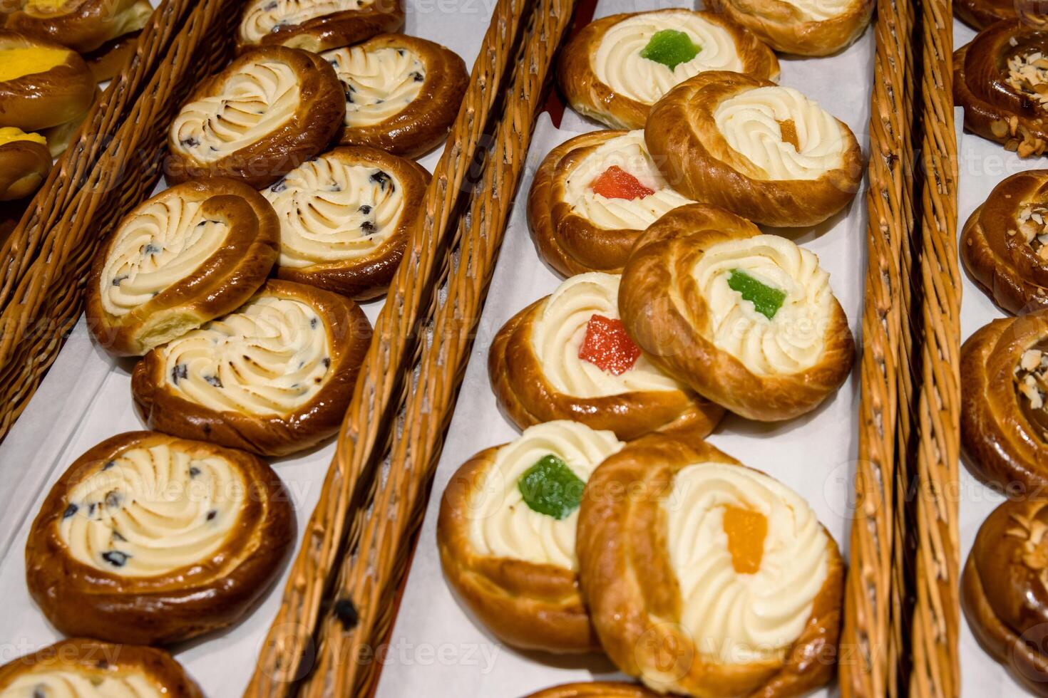 A lot of sweet pastries in baskets on the counter in the food store. Bakery on the buffet table. Business breakfasts and catering at events. Various bread type on shelf. Close-up. Selective focus. photo