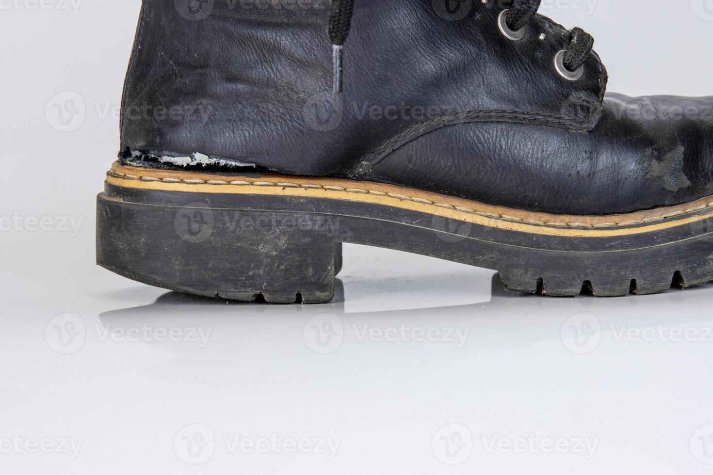 Frontal view of a very worn pair of boots. Old used broken Black Leather lace high Boots. Trendy ankle boots. Stylish womens mens unisex Grunge boots with bootlace. isolated on white background photo