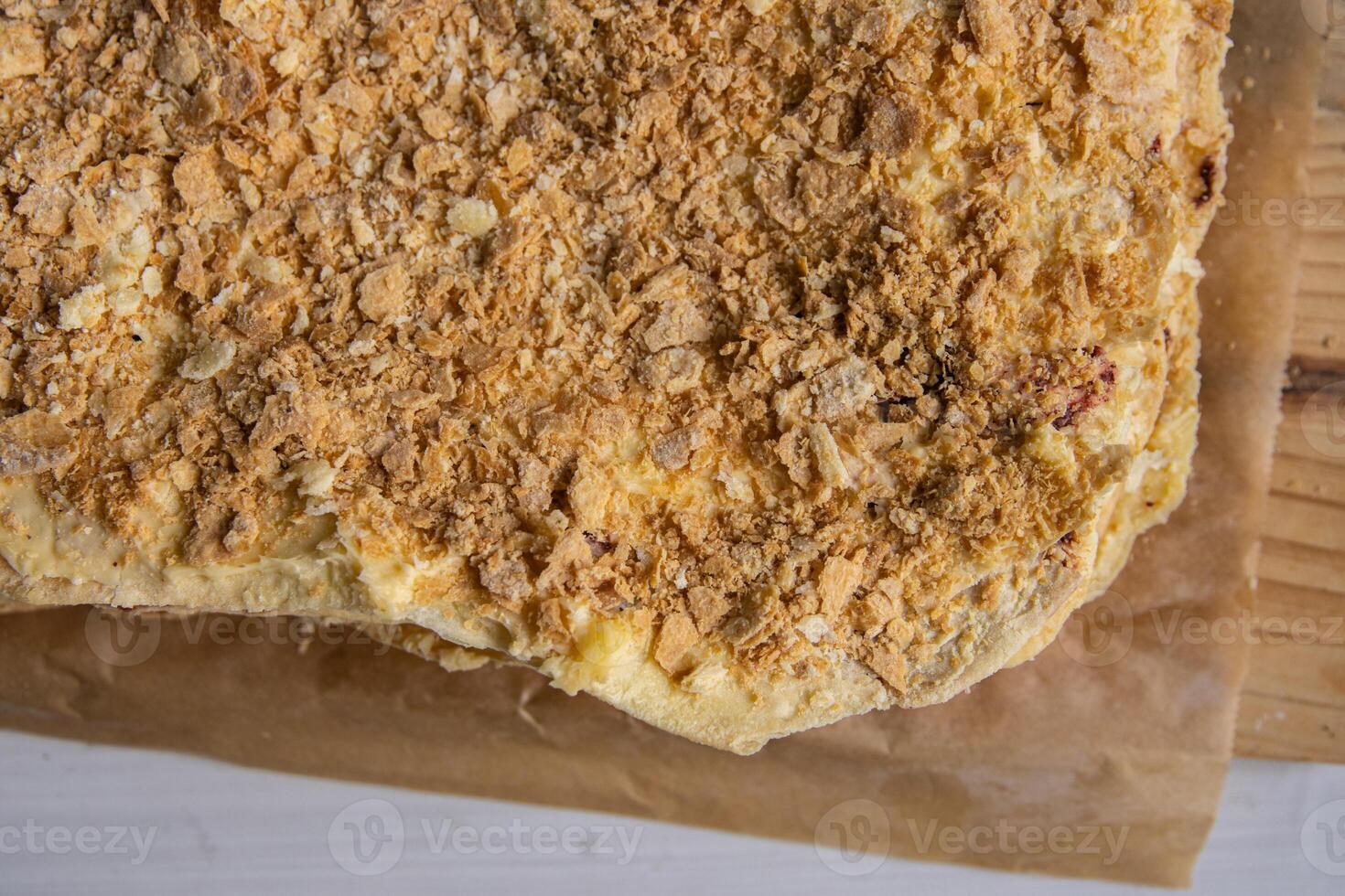 Backing process. Closeup of Puff pastry layers of the French Napoleon cake laying on the backing paper on the wooden cutting board. French pastry with custard butter cream. Top view. Selective focus. photo