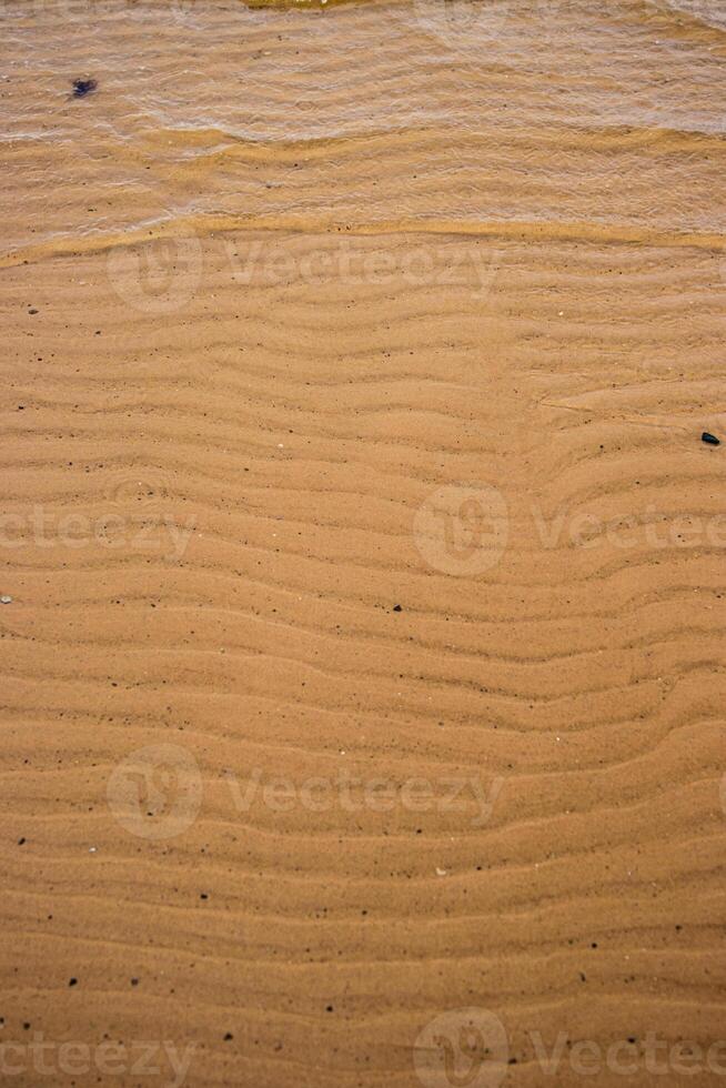 Seamless wet sand with sea water on a whole background. Empty wavy sandy sea bottom. Exotic Sandy Ocean beach surface. Top view. Simple, minimalistic photo. Ideal concept for banner, poster, ads. photo