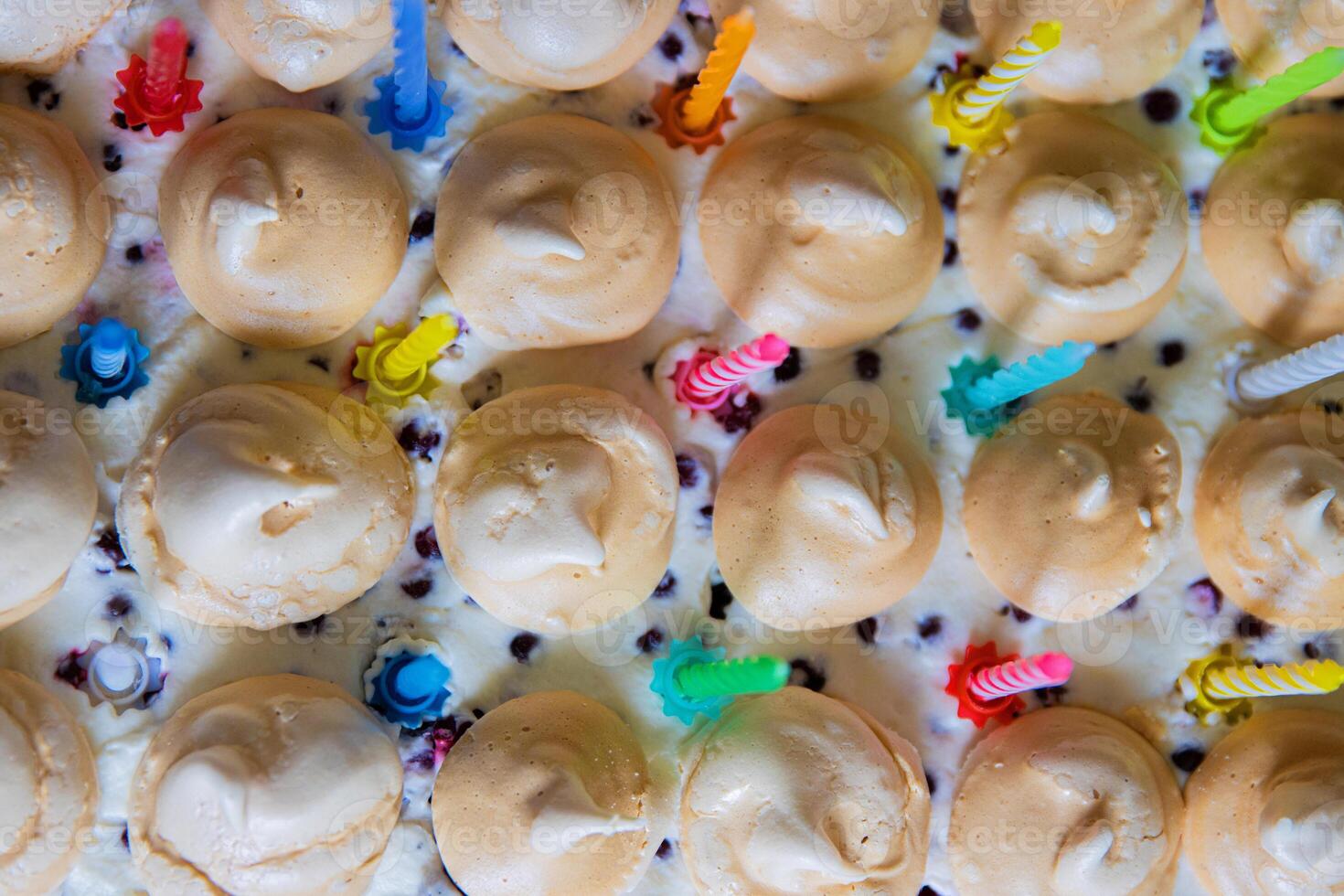 Beautiful Birthday cake with white whipped cream, meringues and cranberries, decorated with multicolored candles. Happy Birthday concept. Pattern for card, poster, banner. Top view. Selective focus photo