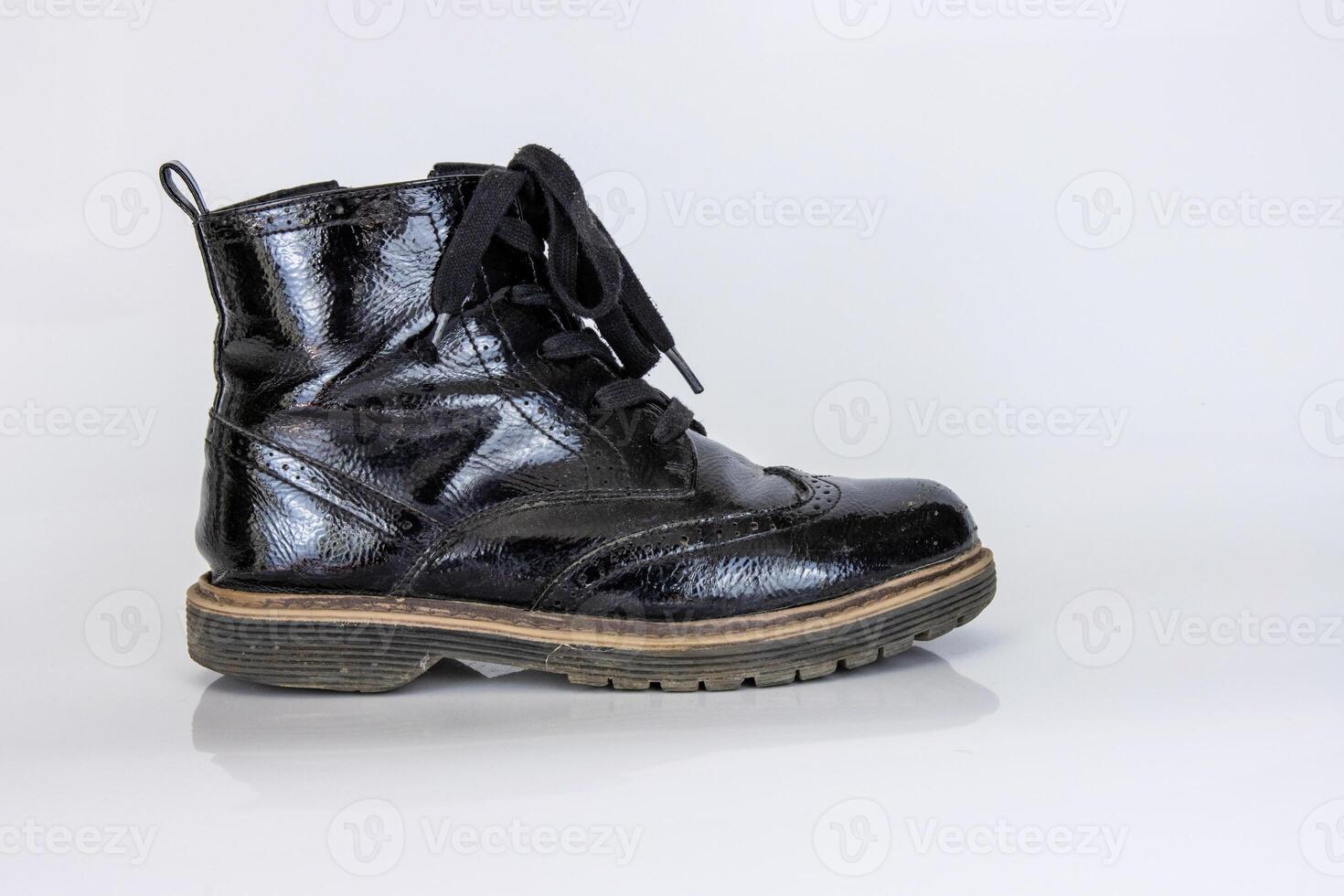 Frontal view of a very worn pair of boots. Old used broken Black Leather lace high Boots. Trendy ankle boots. Stylish womens mens unisex Grunge boots with bootlace. isolated on white background photo