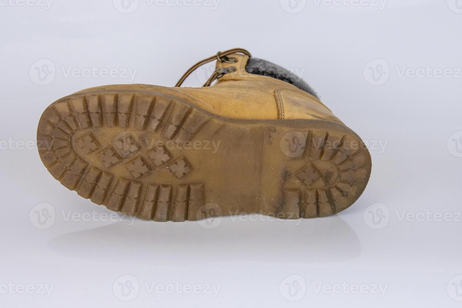 Yellow sole, bottom of hiking trekking lace boots Isolated on white glossy surface with beautiful reflection effect. Second hand tourist walking shoes. Copy Space. White background. photo