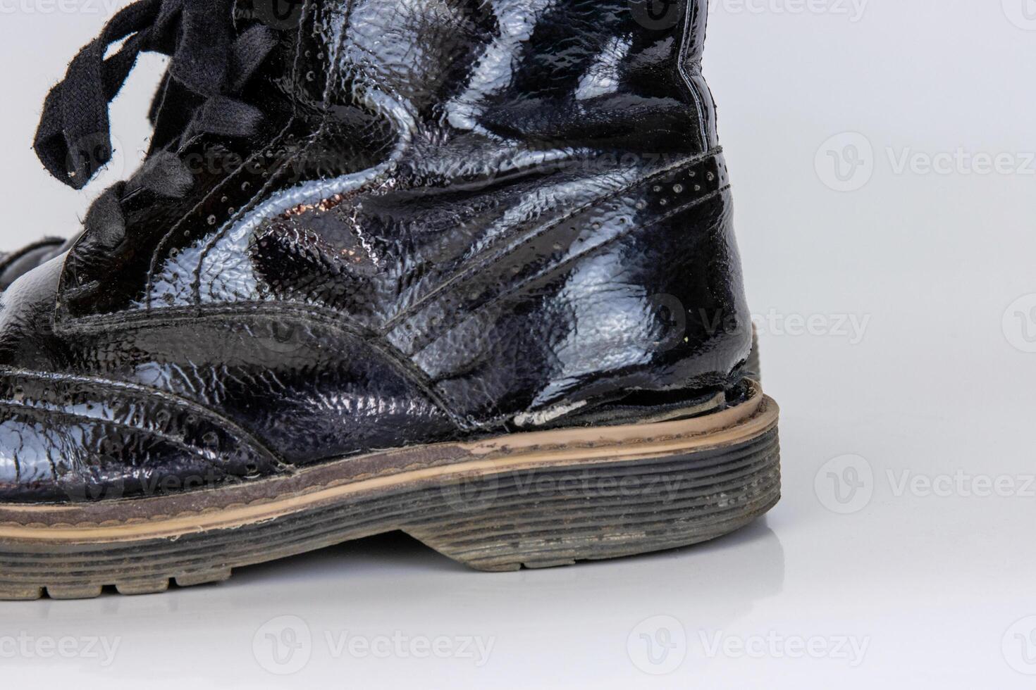 Side view of one very worn boot. Old used broken Black Leather lace high boot. Trendy ankle shoe. Stylish womens mens unisex Grunge boot with bootlace. isolated on white background photo