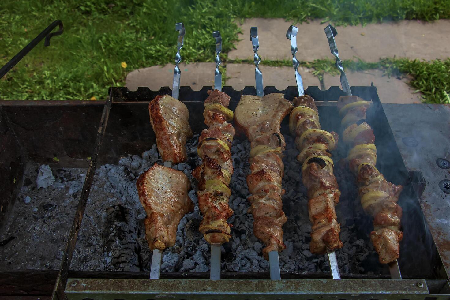 Cooking kebabs on a grill with smoke. Fresh brown BBQ meat cooked on an outdoor grill photo