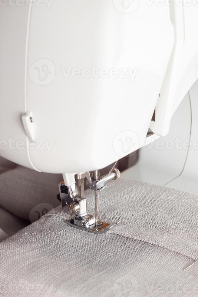 Modern sewing machine presser foot with linen fabric and thread, closeup photo