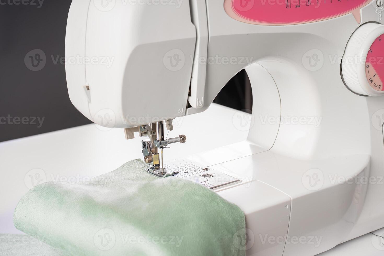 Modern sewing machine presser foot with green fabric and thread photo