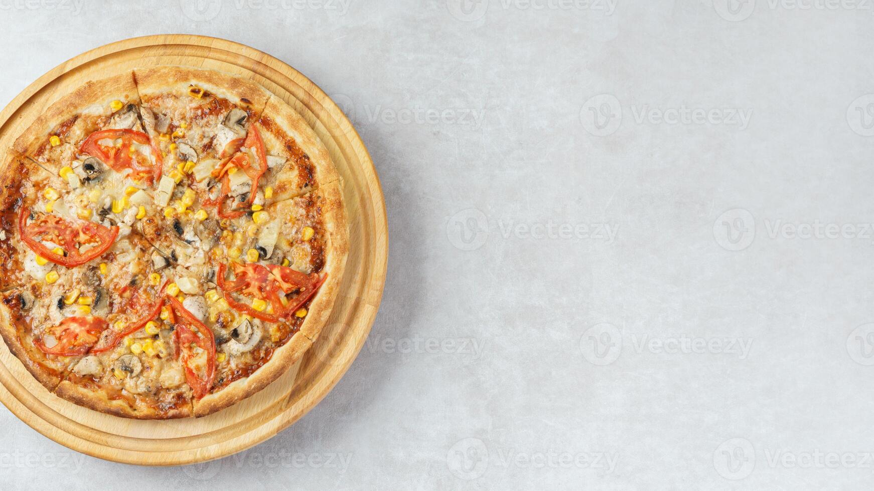 Italian pizza with melted mozzarella cheese mushrooms, corn and tomato on white stone background. photo