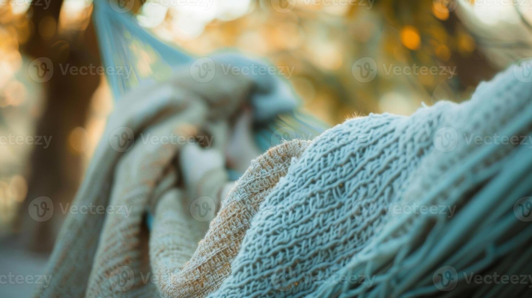 A person lounging in a hammock with a cashmere throw dd over them to protect from the cool breeze photo