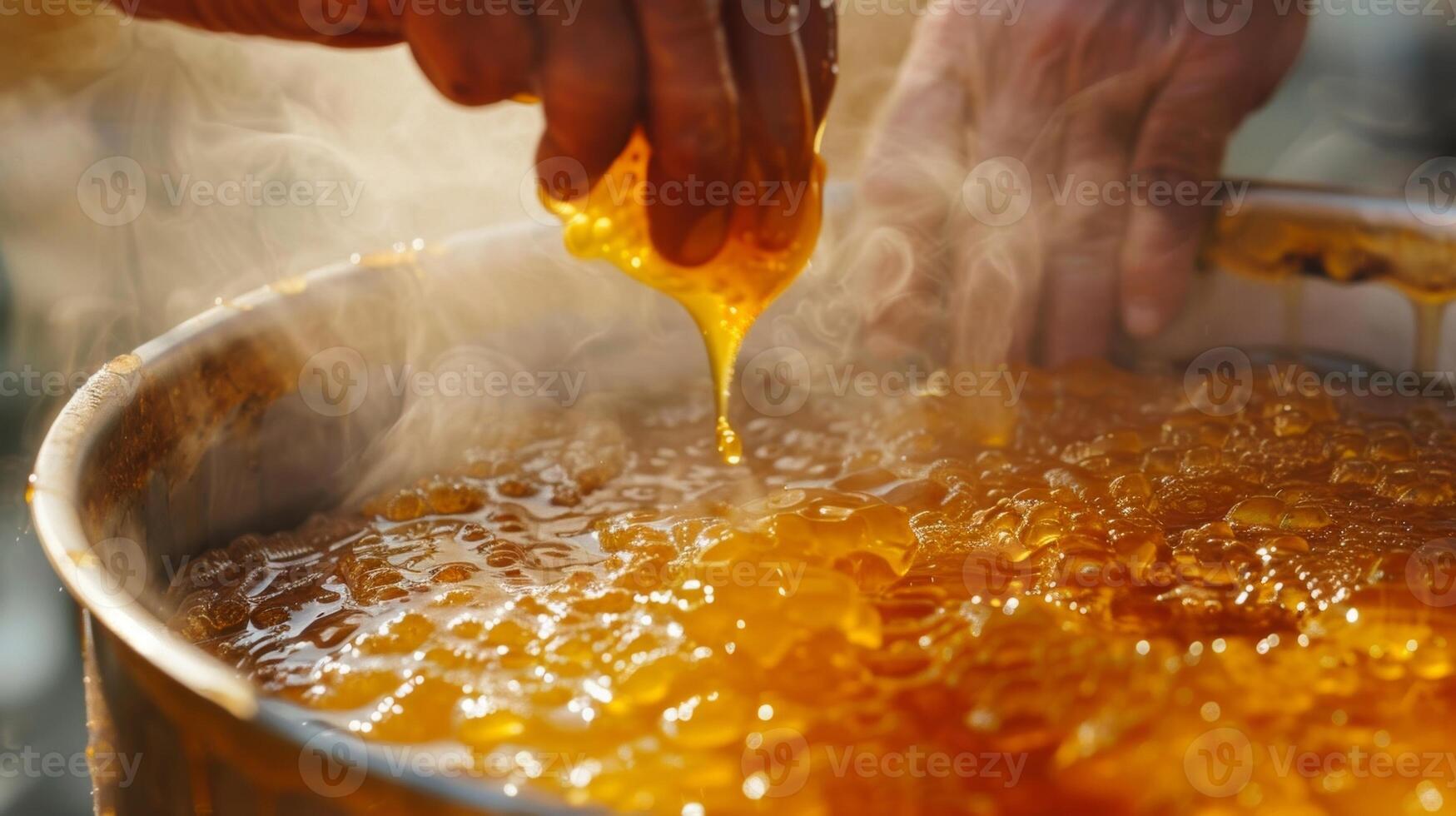 A hand stirring a large pot of freshly harvested honey with steam rising from its sticky surface photo