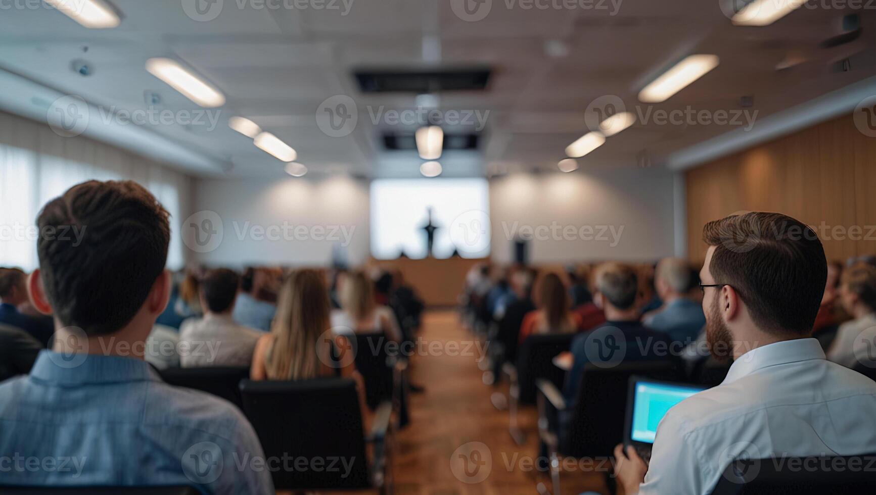 Rear view of people are at business event at the conference hall. On a blurred background the speaker giving a talk. photo